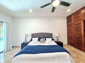Ein Schlafzimmer mit einem Bett, zwei Nachttischen, einem Deckenventilator und einem großen Holzschrank.