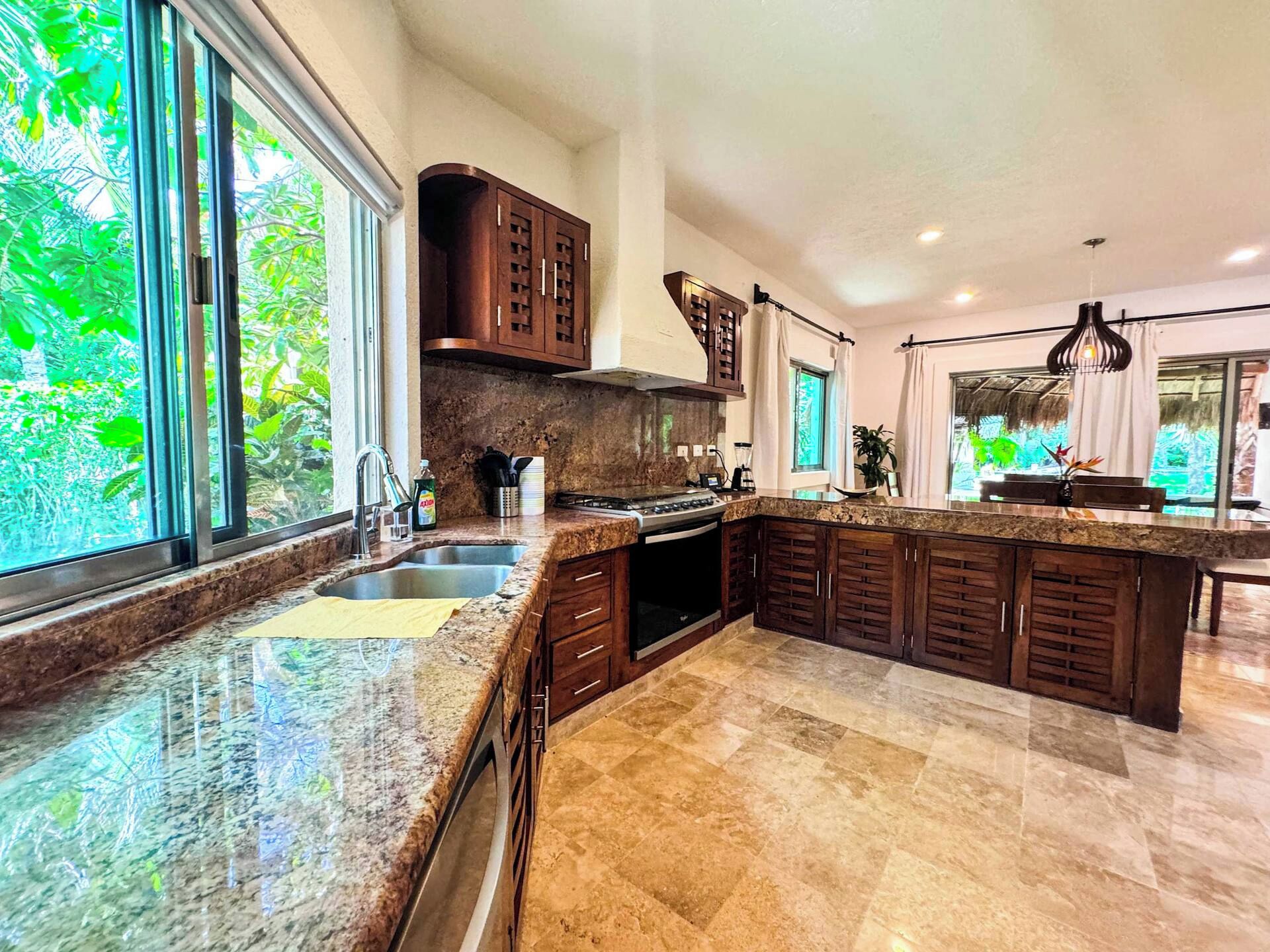A modern kitchen with a large island, granite countertops, and dark wood cabinetry.