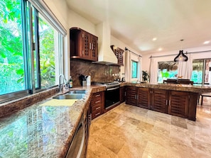 A modern kitchen with a large island, granite countertops, and dark wood cabinetry. - Tropical 3BR retreat w/ pool & beach essentials (Playa del Carmen)