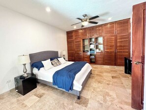 A bedroom with a bed, nightstand, lamp, wardrobe, and ceiling fan. - Tropical 3BR retreat w/ pool & beach essentials (Playa del Carmen)