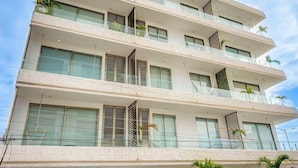Un immeuble à plusieurs étages, doté de balcons, de grandes fenêtres et surplombant un ciel dégagé.
