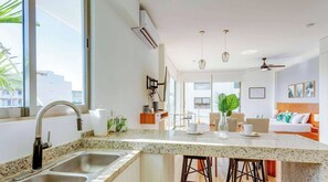 A modern hotel room with a kitchen area, a dining space, and a bedroom. - Ocean-view studio w/ gym, pool & balcony (Playa del Carmen)