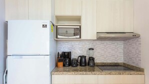 Une cuisine avec un réfrigérateur blanc, un four à micro-ondes, une machine à café et un mixeur sur le plan de travail.