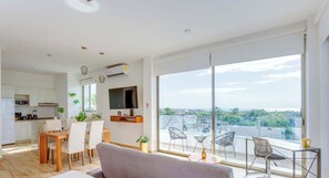 A modern apartment with a dining area, kitchen, living room, and a balcony with a city view. - Ocean-view studio w/ gym, pool & balcony (Playa del Carmen)