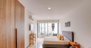 A bedroom with a bed, bedside table, and a view of the outside. - Rooftop Pool Vibes | Steps to 5th Avenue & Beach (Playa del Carmen)