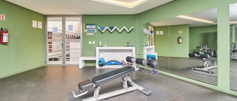 Una palestra con attrezzature per esercizi, uno specchio e pareti verdi.