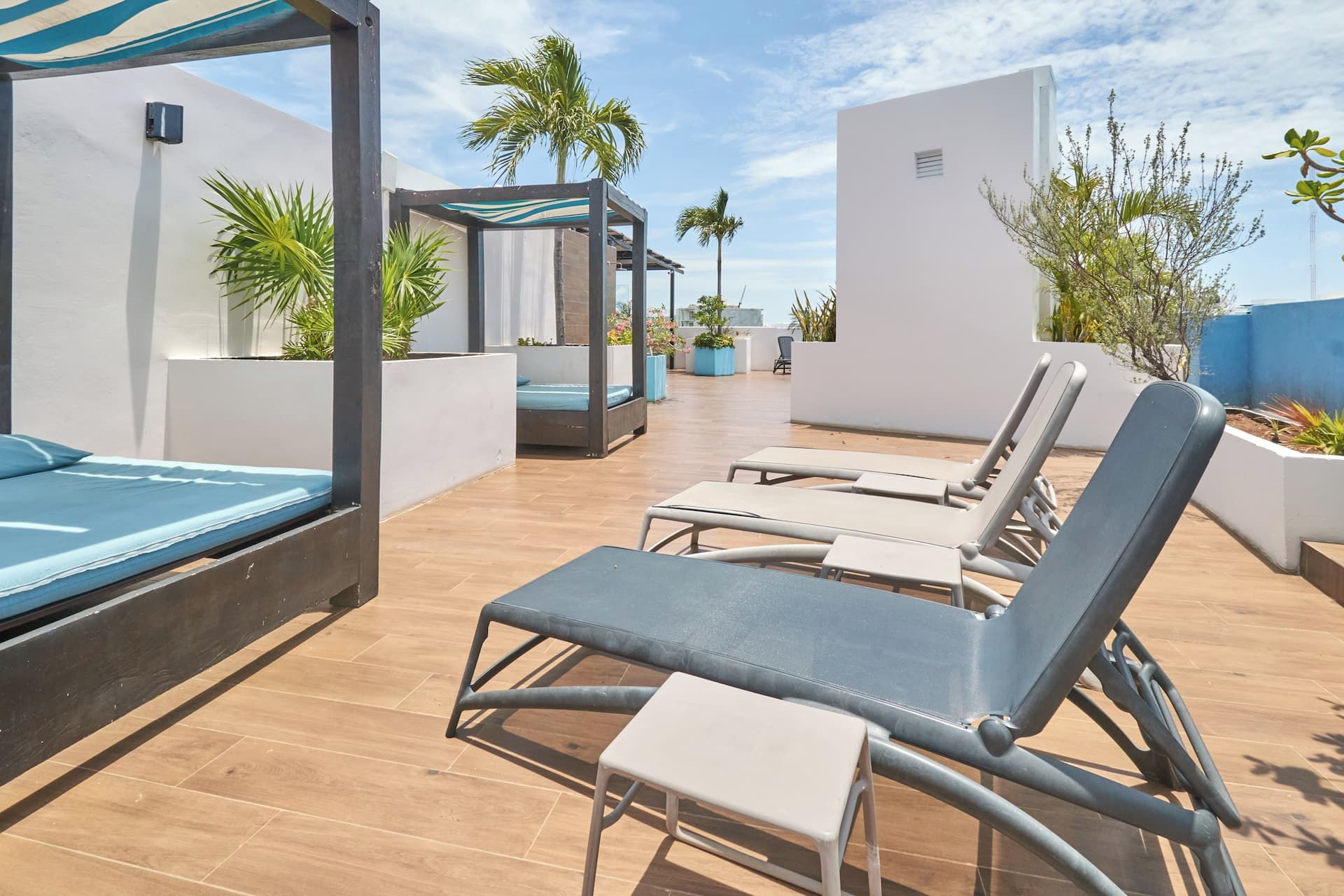 Eine Dachterrasse mit Liegestühlen, einem kleinen Tisch und einer überdachten Sitzecke.