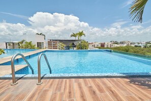 A rooftop swimming pool with a clear blue sky and distant buildings. - 2BR w/ dual pools, near beach & 5th Ave (Playa del Carmen)