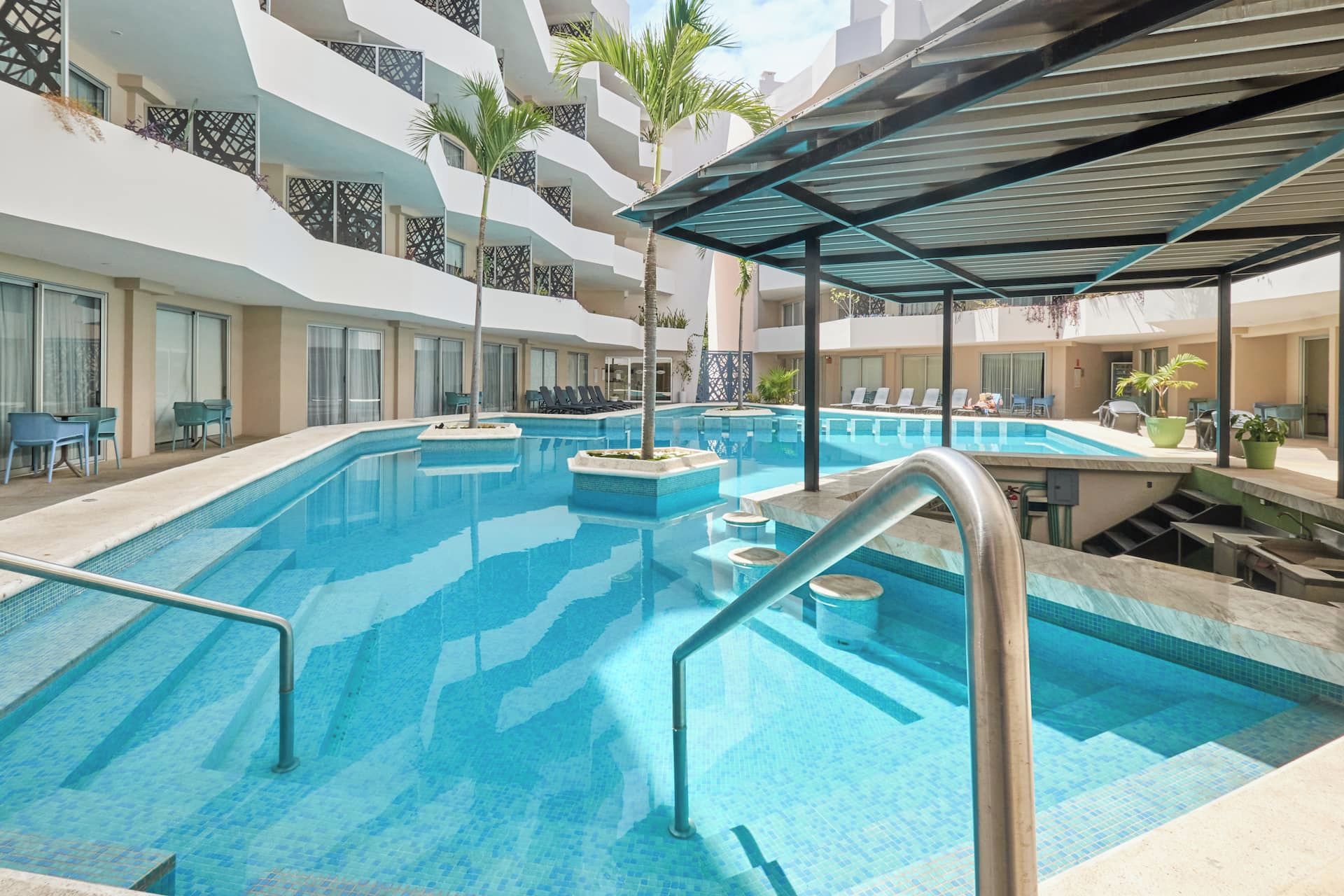 Ein Schwimmbecken mit mehreren Bahnen, umgeben von Liegestühlen und einer überdachten Sitzgelegenheit.