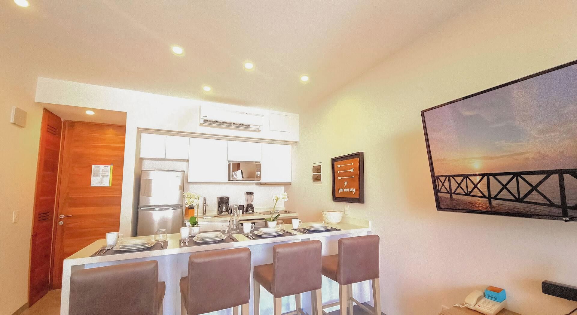 A modern kitchen with a dining area, equipped with a refrigerator, stove, and coffee maker.
