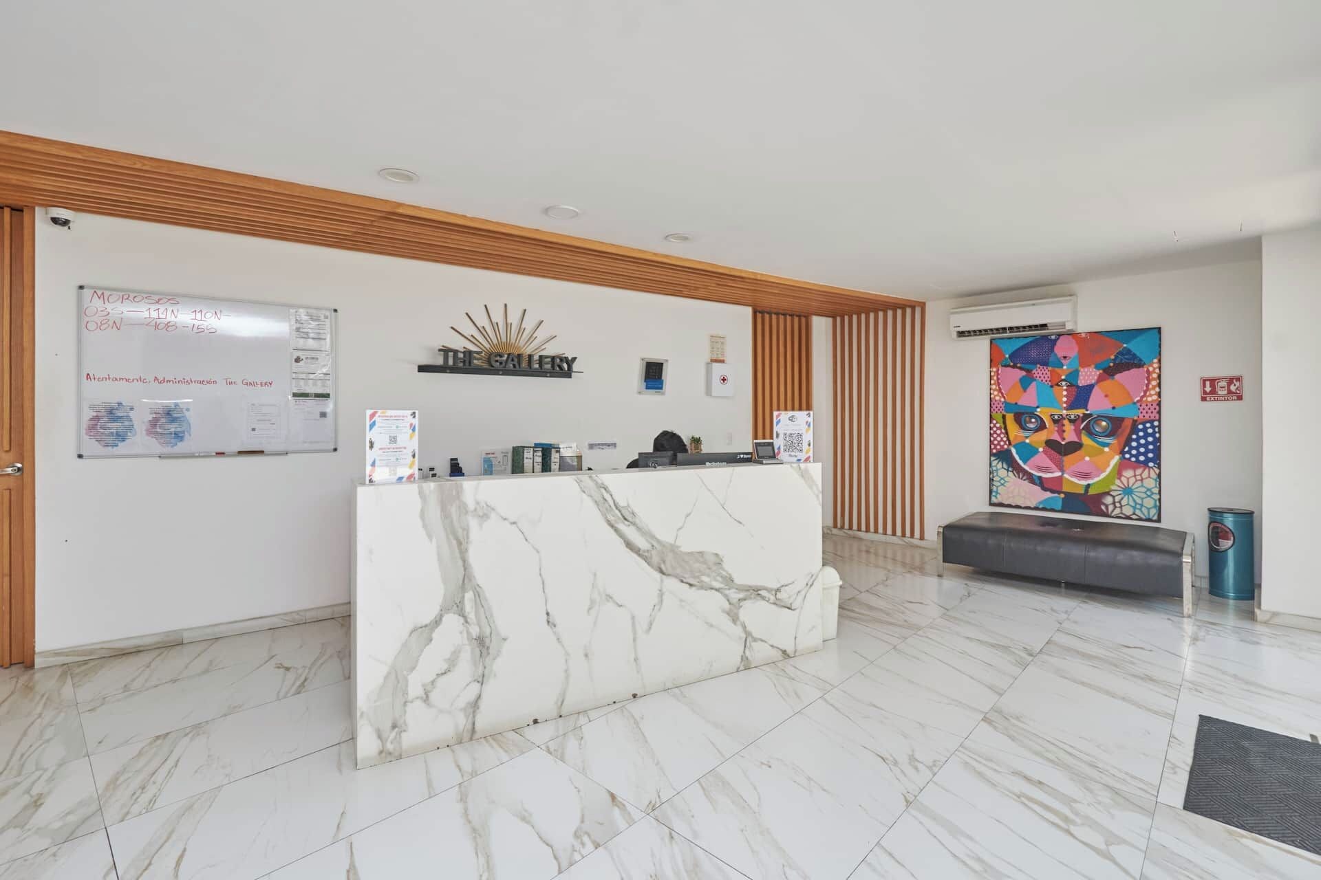 A reception area with a marble counter, a whiteboard with handwritten notes, and a colorful abstract painting on the wall.