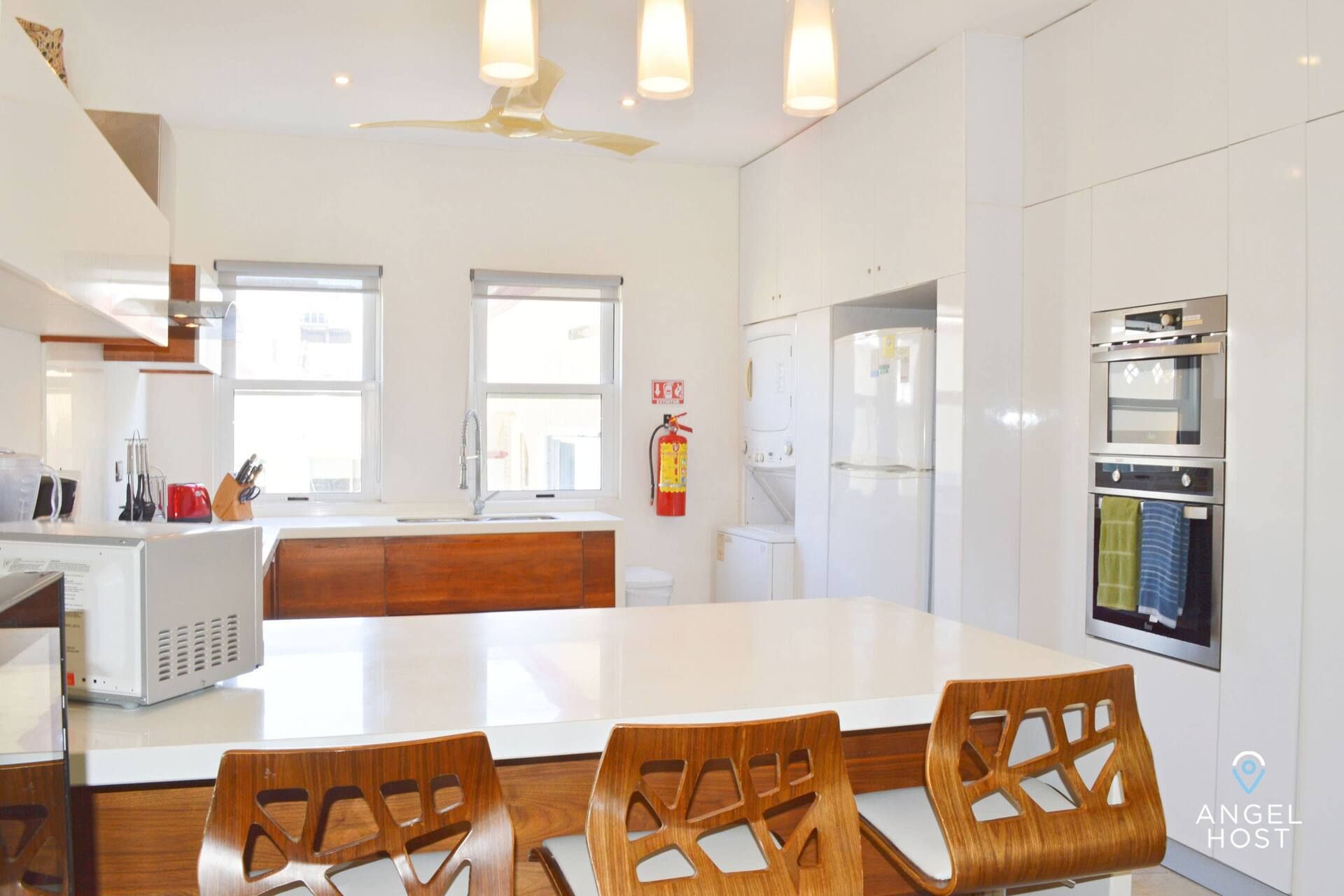 Una cocina moderna con armarios blancos, una isla central y un horno empotrado.