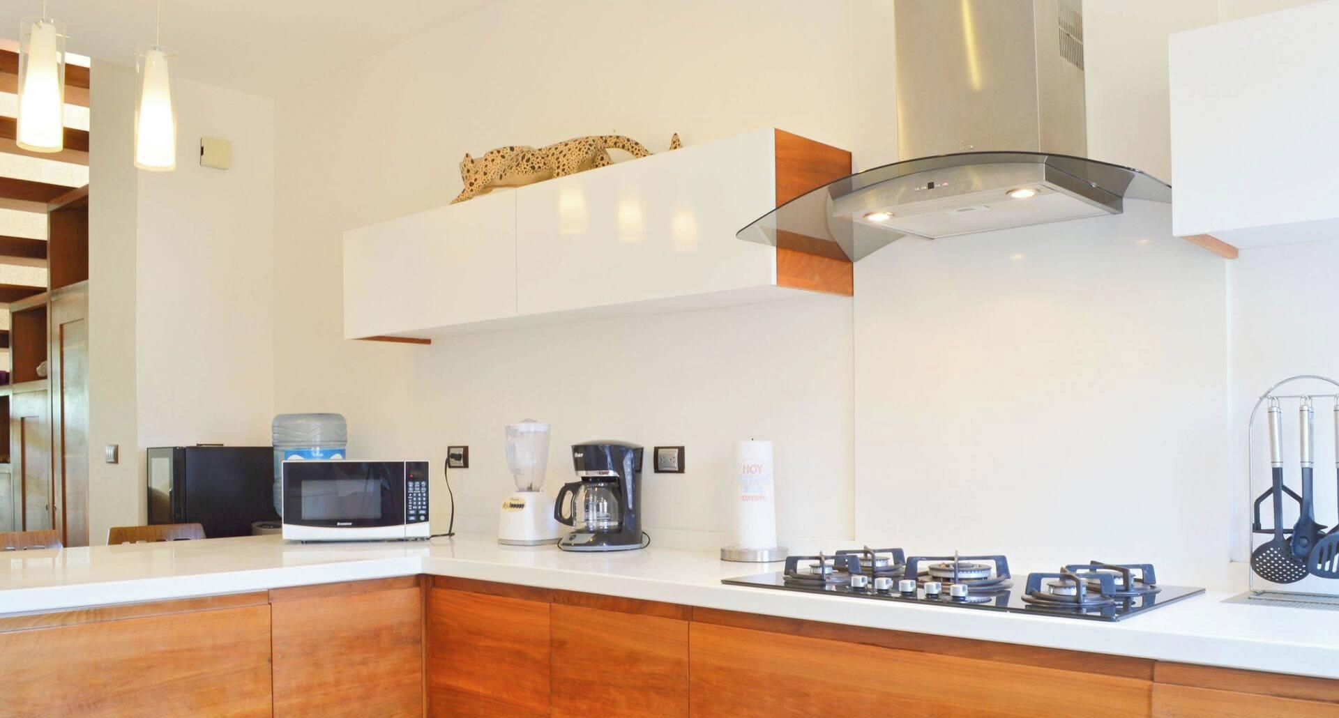 Una cocina moderna con microondas, cafetera y cocina a gas.