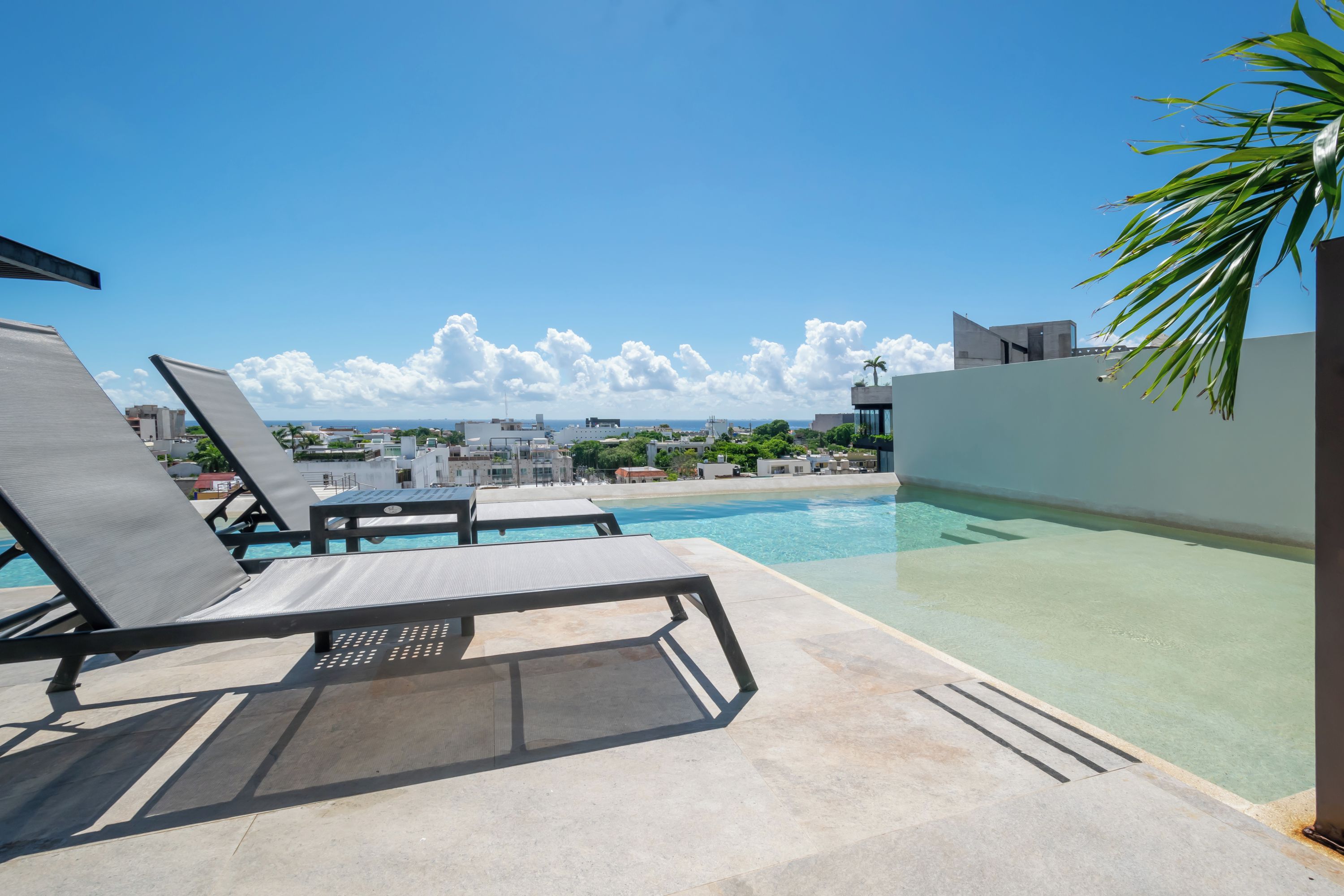 Un espace piscine aménagé sur le toit, avec des chaises longues et une vue sur le paysage urbain.
