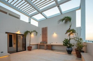A modern outdoor space with a glass ceiling, a seating area, and potted plants. - Beachside escape w/ rooftop pool access (Playa del Carmen)