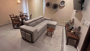 Un soggiorno moderno con un divano componibile, un tavolo da pranzo con sedie, decorazioni a parete e una ventola a soffitto.