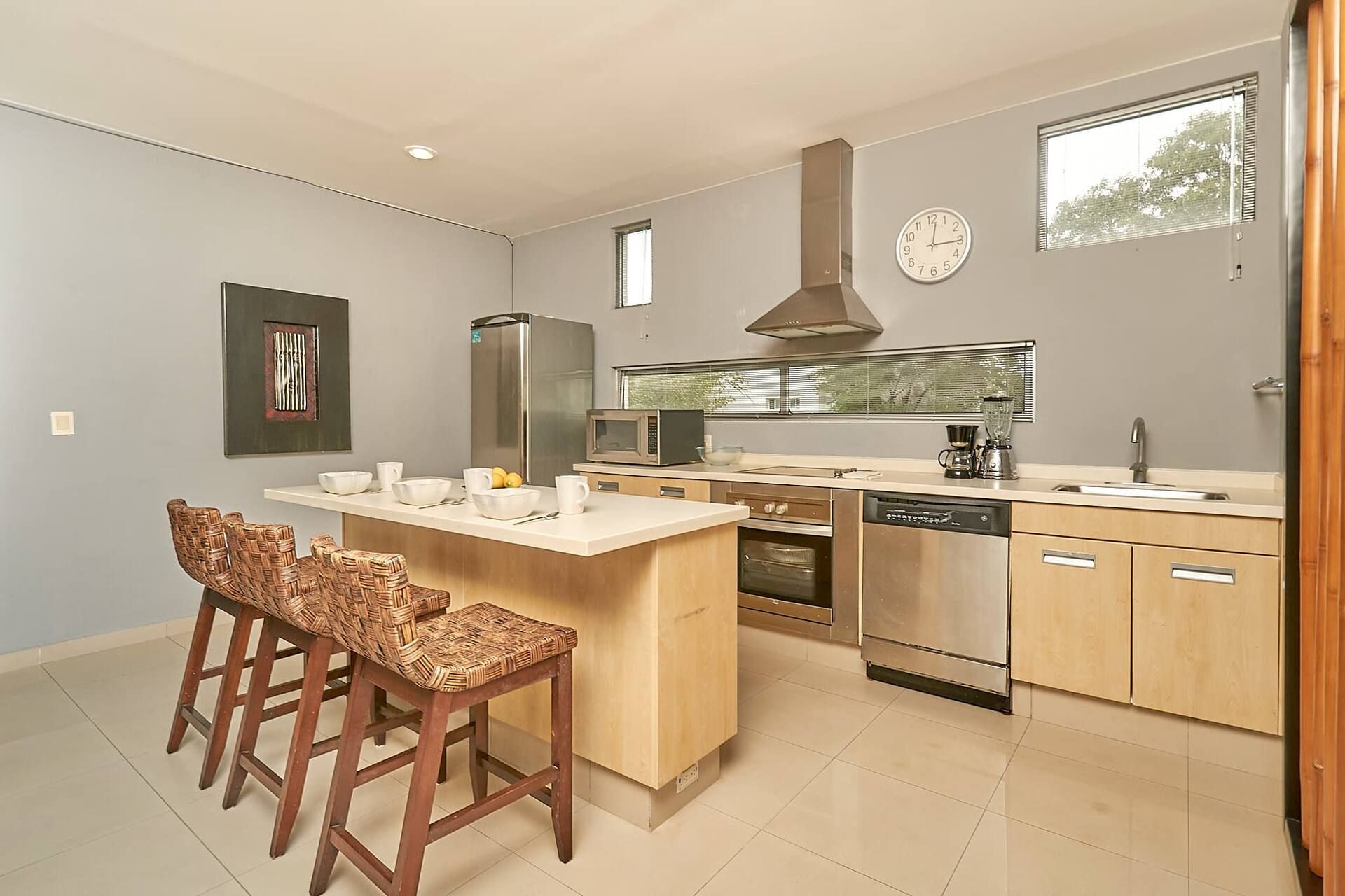Een moderne keuken met een centraal eiland, inbouwapparatuur en een groot raam.