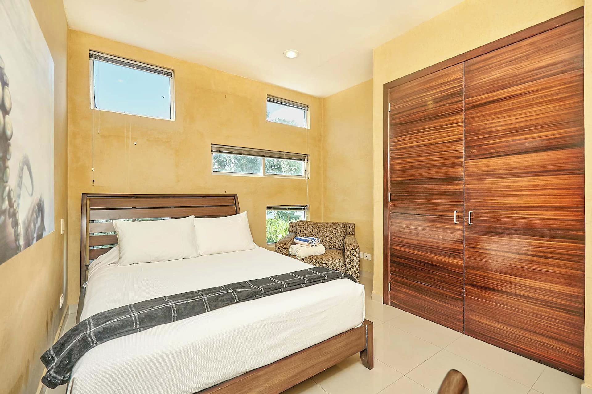 A bedroom with a bed, a wardrobe, and two windows.