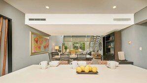 A modern dining area with a central island, chairs, and a table set for four. - 3BR condo w/ pool & BBQ grill (Playa del Carmen)