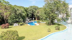 A swimming pool surrounded by lush greenery and a clear sky. - 3BR condo w/ pool & BBQ grill (Playa del Carmen)