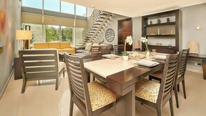 A modern dining area with a large table, multiple chairs, and a staircase leading to an upper level. - 3BR condo w/ pool & BBQ grill (Playa del Carmen)
