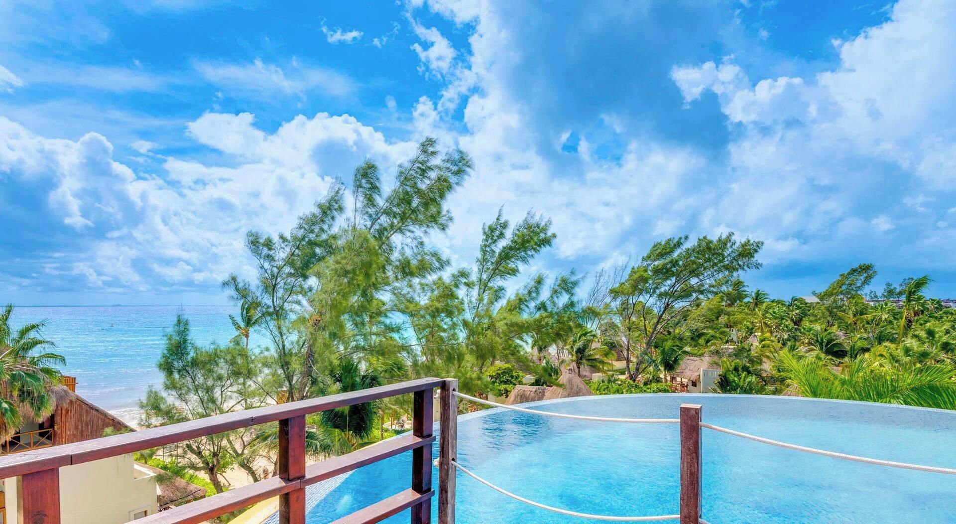 Une piscine avec une terrasse en bois et vue sur l’océan.