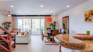 A modern living room with a dining area, a staircase, and a kitchen counter. - Penthouse w/ private terrace & rooftop pool (Playa del Carmen)