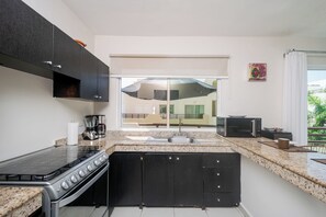 A modern kitchen with a gas stove, a coffee maker, and a microwave. - Penthouse retreat | rooftop, BBQ & pool (Playa del Carmen)