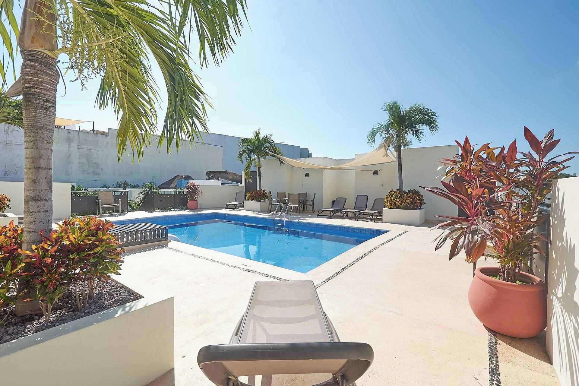 A swimming pool with lounge chairs and potted plants.