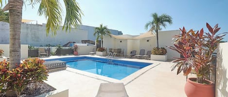 A swimming pool with lounge chairs and potted plants.