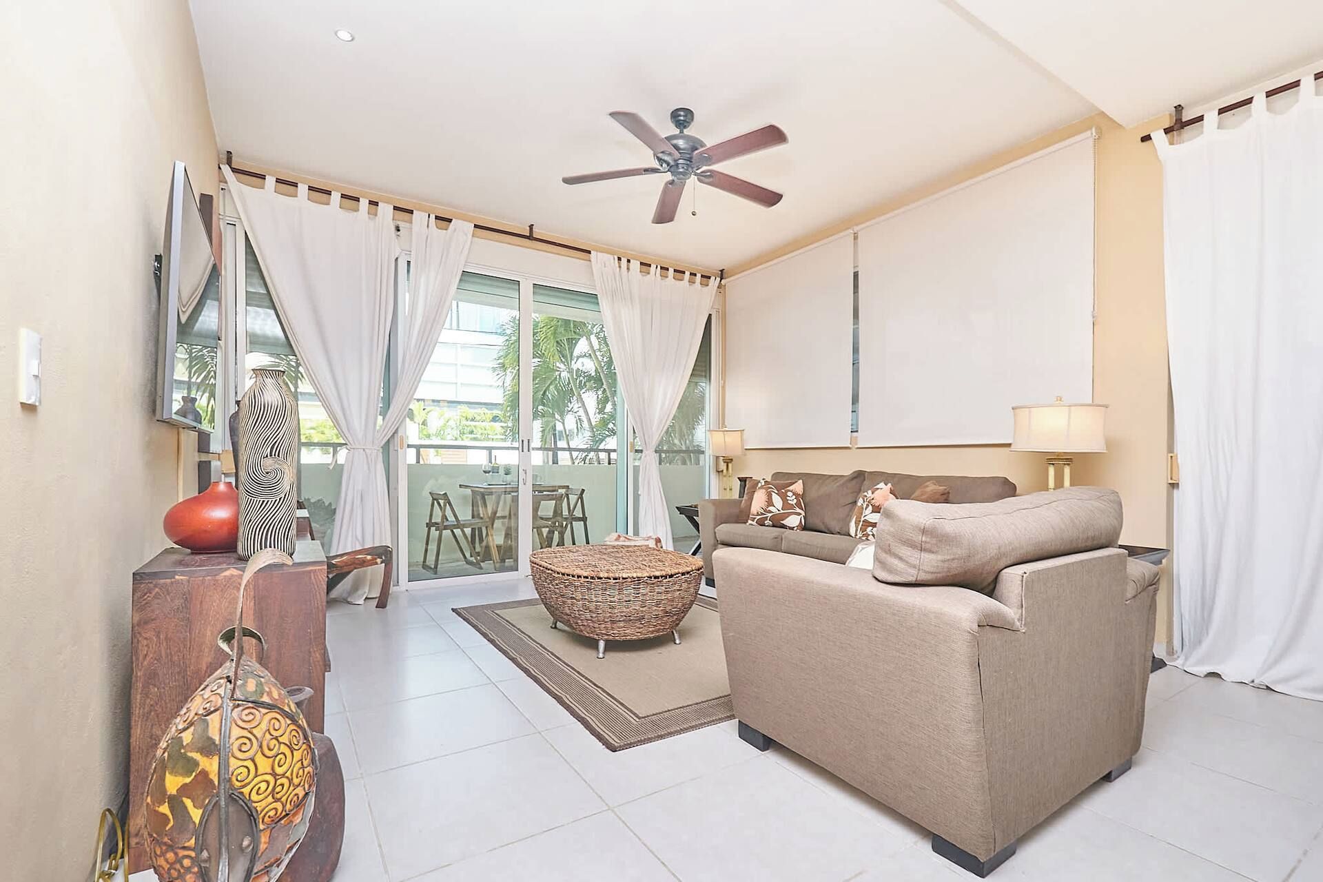 Ein Wohnzimmer mit Deckenventilator, einer Couch, einem Couchtisch und einem Essbereich mit Stühlen.