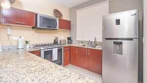 Eine Küche mit Granit Arbeitsplatten, Edelstahlgeräten und Holzschränken.