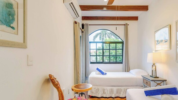 A hotel room with a bed, a small round table, a chair, a window with curtains, and a ceiling fan. - 6BR villa w/ pool, BBQ & backyard (Playa del Carmen)