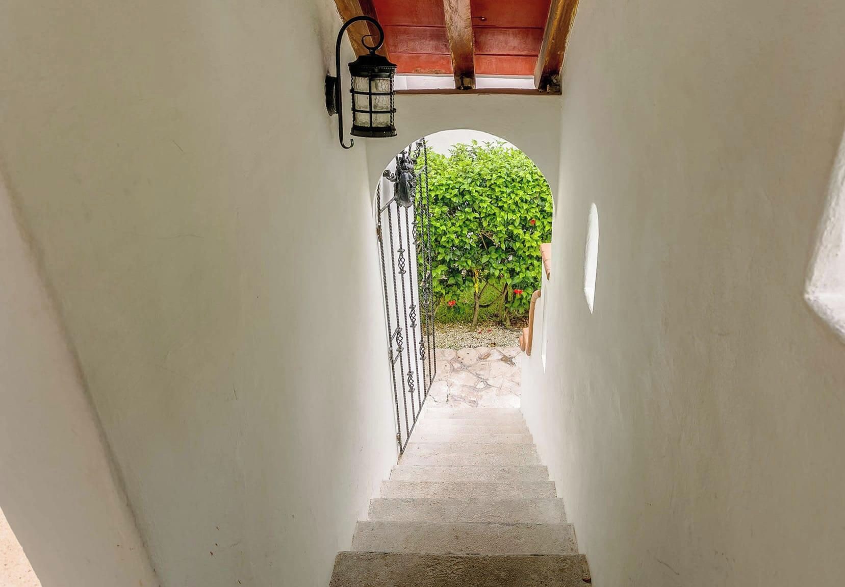 A narrow stairway leading to a covered outdoor area with a metal gate and a lantern.