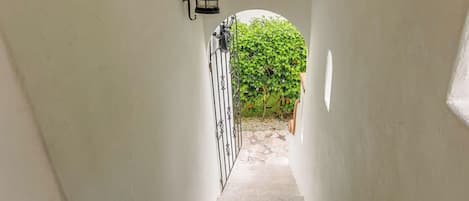 A narrow stairway leading to a covered outdoor area with a metal gate and a lantern.