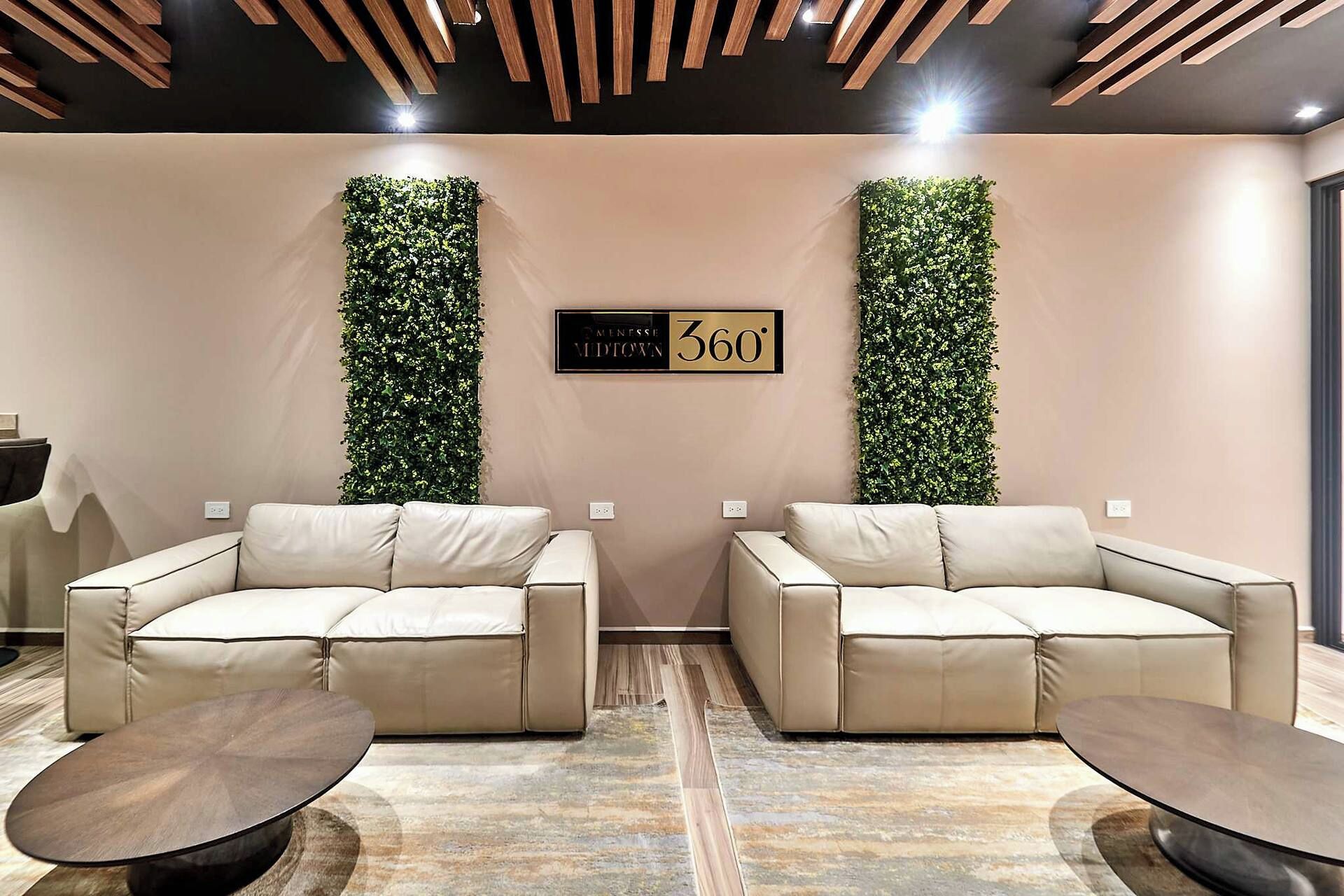 A modern waiting area with two sofas, a reception desk, and a wall-mounted sign.