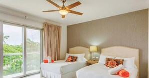 A hotel room with two beds, a ceiling fan, a large window with curtains, and a view of greenery outside. - Tranquil Zen Escape | Spa, Gym, Beachfront Pools (Playa del Carmen)
