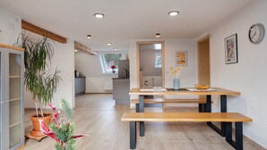 Una cucina moderna con un tavolo e una panca di legno, una pianta in vaso e vista sull'area pranzo.