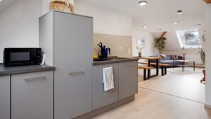 Una cucina moderna con forno a microonde integrato, un armadietto grigio e un'area pranzo con tavolo e sedie.