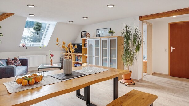 Un soggiorno moderno con un tavolo da pranzo in legno, un divano e una libreria.