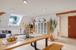 A modern living room with a wooden dining table, a sofa, and a bookshelf. - Apartment 'Haus An Der Breg' with Wi-Fi (Vöhrenbach-Hammereisenbach)