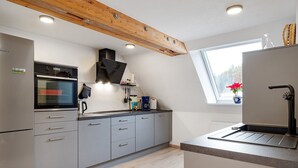 Una cucina moderna con mobili grigi, forno integrato e finestra vista alberi.
