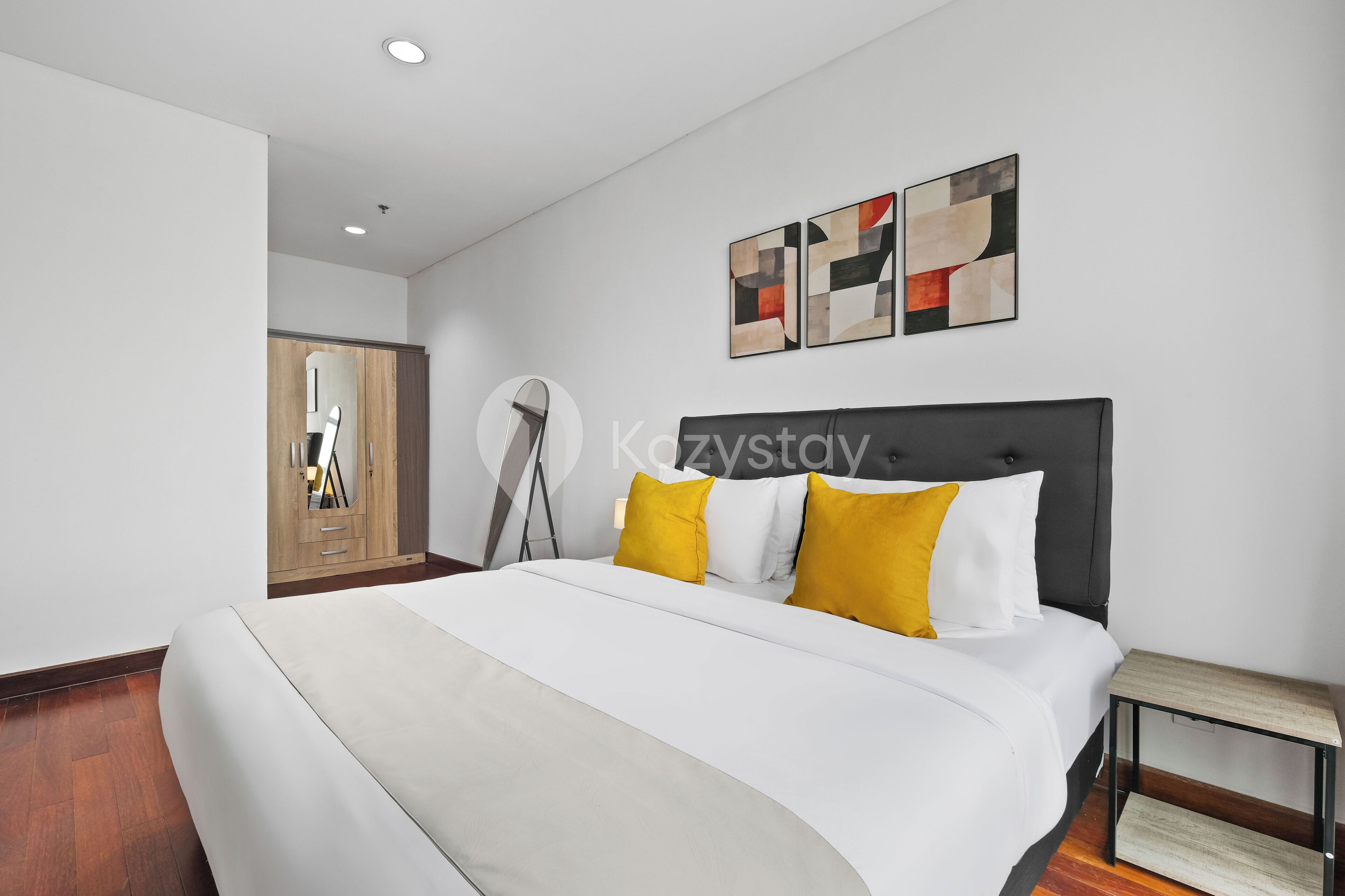 Una habitación de hotel moderna con una cama grande, un armario de madera y arte abstracto en la pared.