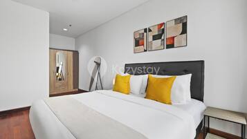 Una habitación de hotel moderna con una cama grande, un armario de madera y arte abstracto en la pared.