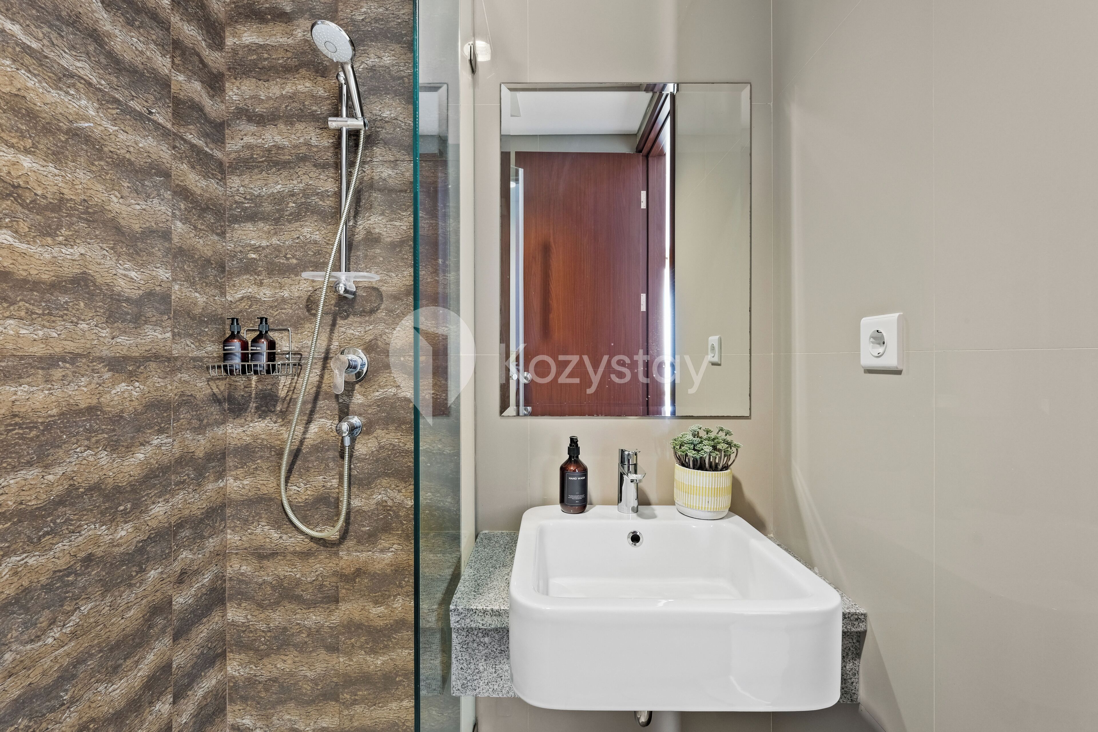 A modern bathroom with a glass shower enclosure, a white sink, and a mirror above it.