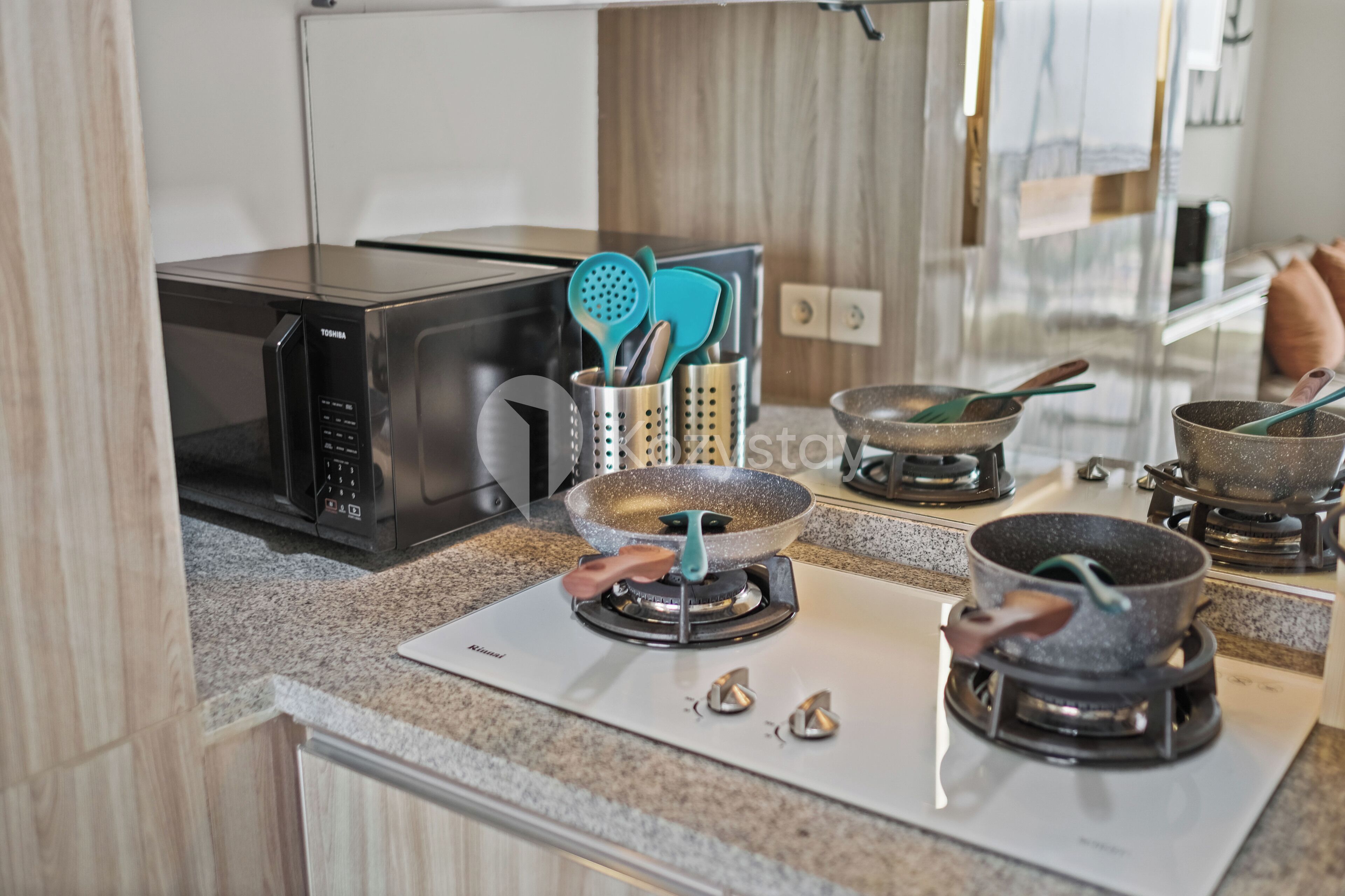 Une cuisine équipée d’un four à micro-ondes, d’une cuisinière à gaz et d’ustensiles de cuisine.
