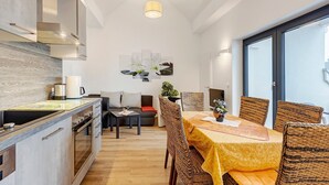 A modern kitchen with a dining area, a sofa, and a table with chairs. - Deluxe Apartment Lea with Balcony and Wi-Fi (Radolfzell am Bodensee)