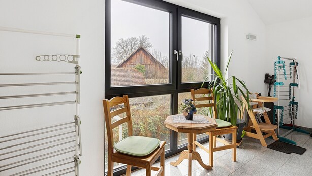 A room with a large window, wooden chairs, a small table, and a radiator. - Deluxe Apartment Lea with Balcony and Wi-Fi (Radolfzell am Bodensee)