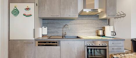 A modern kitchen with a dishwasher, oven, and stainless steel appliances.