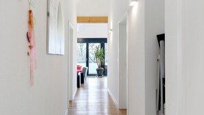 Ein Flur mit Holzboden, weißen Wänden und einer Tür am Ende.